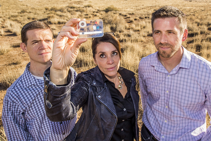 3 scientists looking at a chip on a card