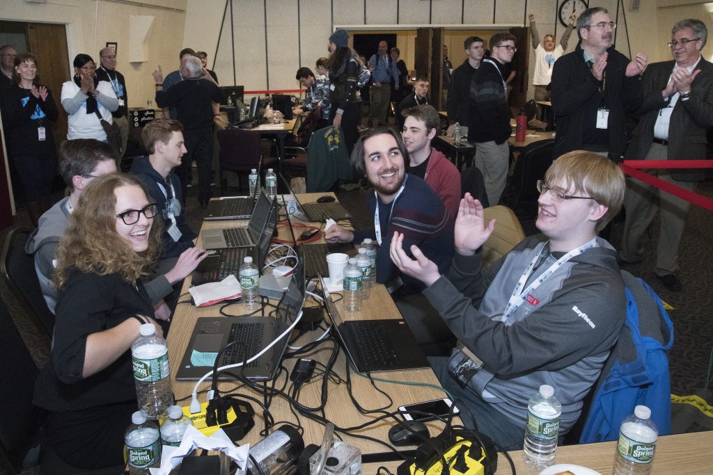 A team around a table claps after the winner is announced at a CyberForce event at Purdue.