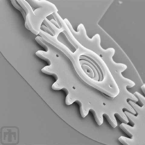 A microengine gear meshes with another gear.