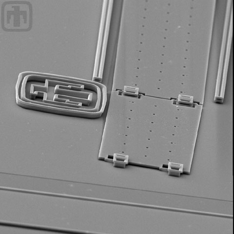 This image of a pop-up mirror, taken at an angle, includes the Sandia National Laboratories Thunderbird Logo and the hinges on the linear rack.