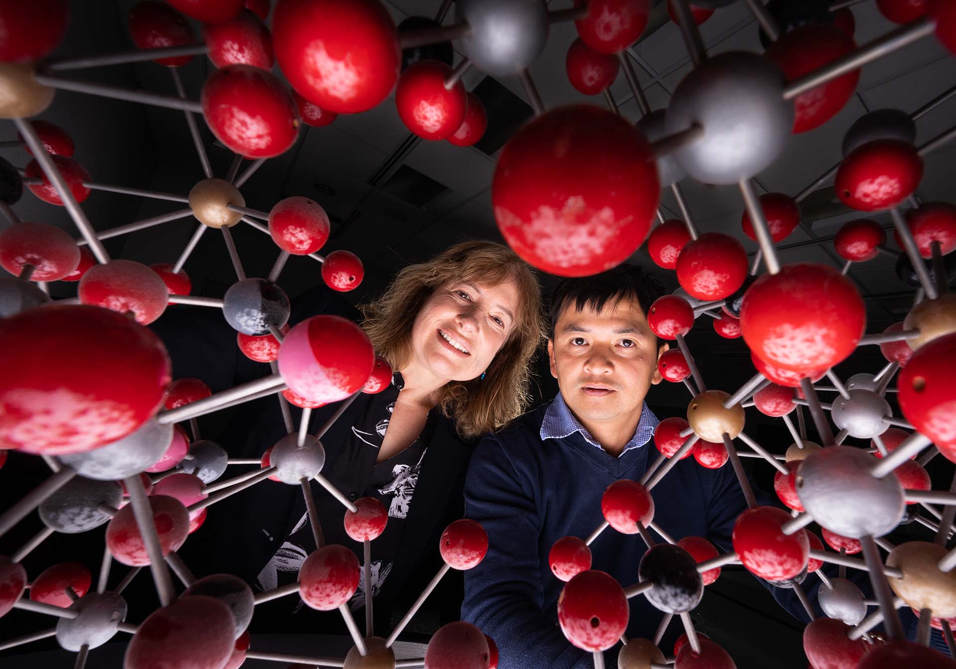 A Sandia bioengineer and chemical engineer peer through a large chemical representation of a kind of clay.