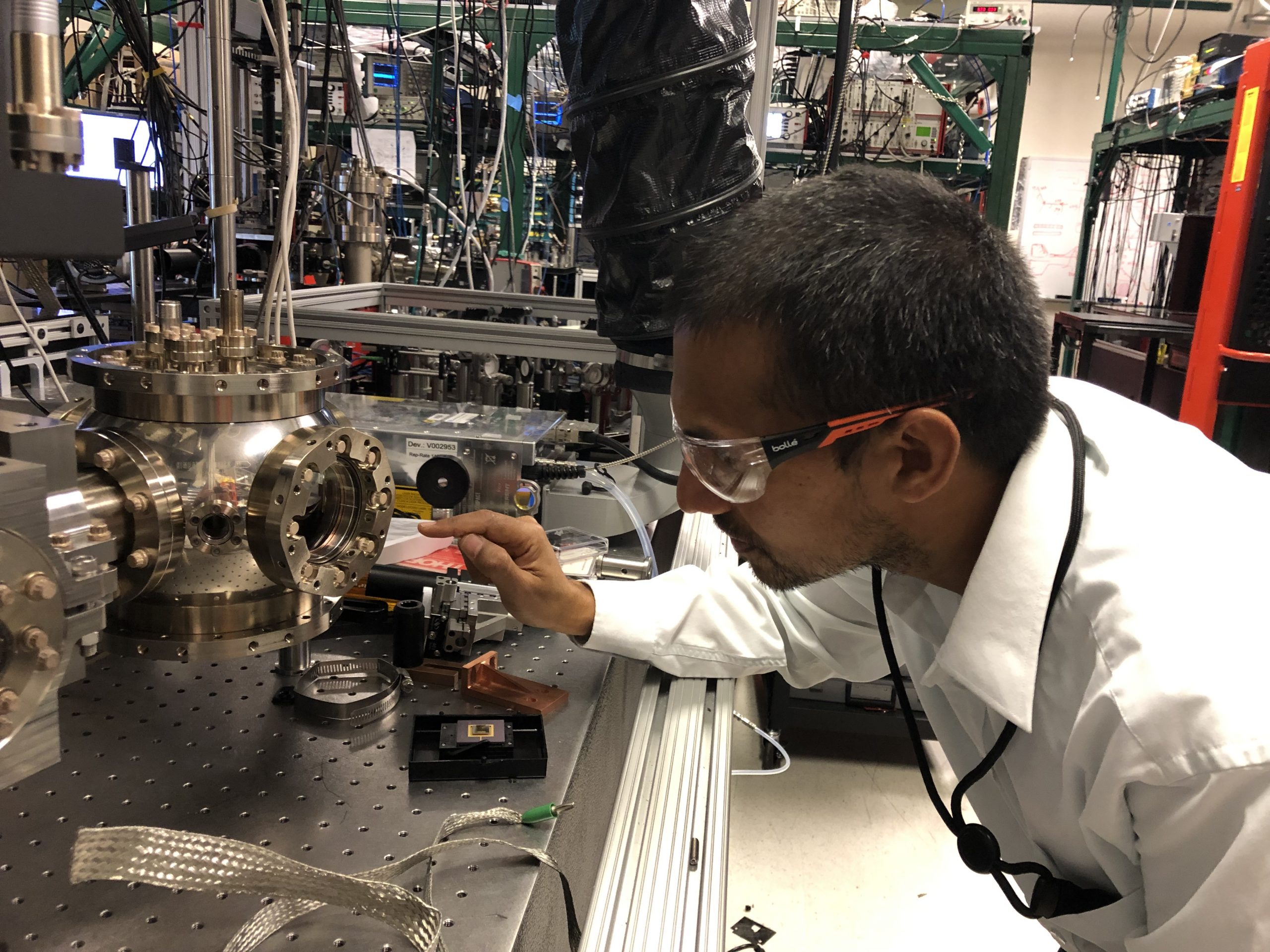 Bishnu Khanal, Sandia R&D manager, leans down to work on an ion trapping system
