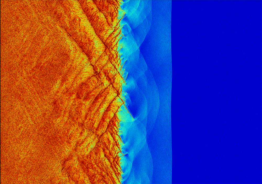 DIAMOND BREAKDOWN — This multibillion atom simulation of shockwave propagation into initially uncompressed diamond (blue) uses Sandia’s high-accuracy SNAP, or Spectral Neighbor Analysis Potential, model to predict that the final state (orange) is formed by recrystallization of amorphous cracks (red) that take shape in the light blue, green and yellow compressed material. (Computer image by Aidan Thompson)