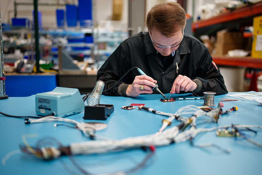 An electrical engineer works on soldering for Core SkyFox. The project includes the use of commercial off-the-shelf parts and systems for rapid prototyping and testing of hypersonic flight testing. (Photo by Craig Fritz)