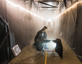Sandia developed a fog chamber to test optics, like security camera sensors, in a controlled environment. Sandia chemical engineer Andres Sanchez checks an instrument that measures the particle size and concentration of the fog in the chamber’s atmosphere. (Photo by Randy Montoya)