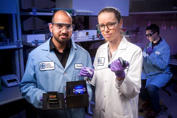 Sandia scientists holding device in lab