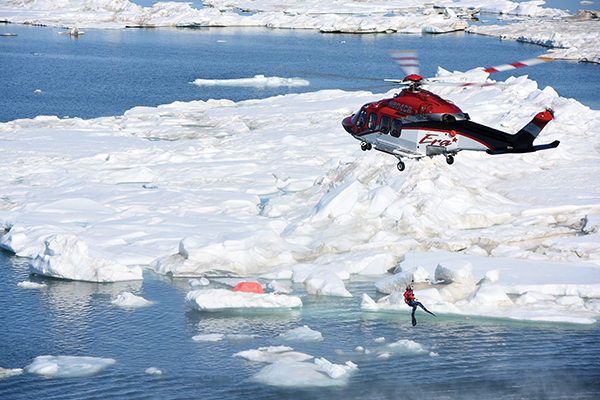An Era Helicopters crew lowers a Priority 1 Air Rescue swimmer into the Arctic Ocean during a joint search and rescue exercise near Oliktok Point, Alaska, July 13, 2015. The Era and Priority 1 crew joined the Coast Guard Research and Development Center, ConocoPhillips Co. and Insitu Inc. to assess unmanned aircraft systems for use in Search and Rescue and to further understand how to collaborate on the North Slope during response operations. U.S. Coast Guard photo by Petty Officer 2nd Class Grant DeVuyst.