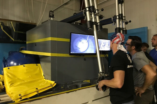 technicians operate manipulator arms of the Mobile Hot Cell