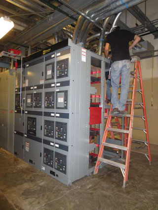 A FACILITIES MANAGEMENT ELECTRICIAN installs new electrical equipment in an Area 1 building.