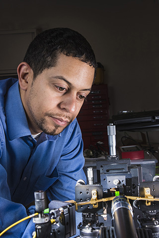 SOMETHING NEW IN THE WORLD — Sandia researcher Charles Reinke studies a tiny phononic/photonic filter on a green, stamp-sized substrate toward the picture's bottom-right.	(Photo by Randy Montoya)