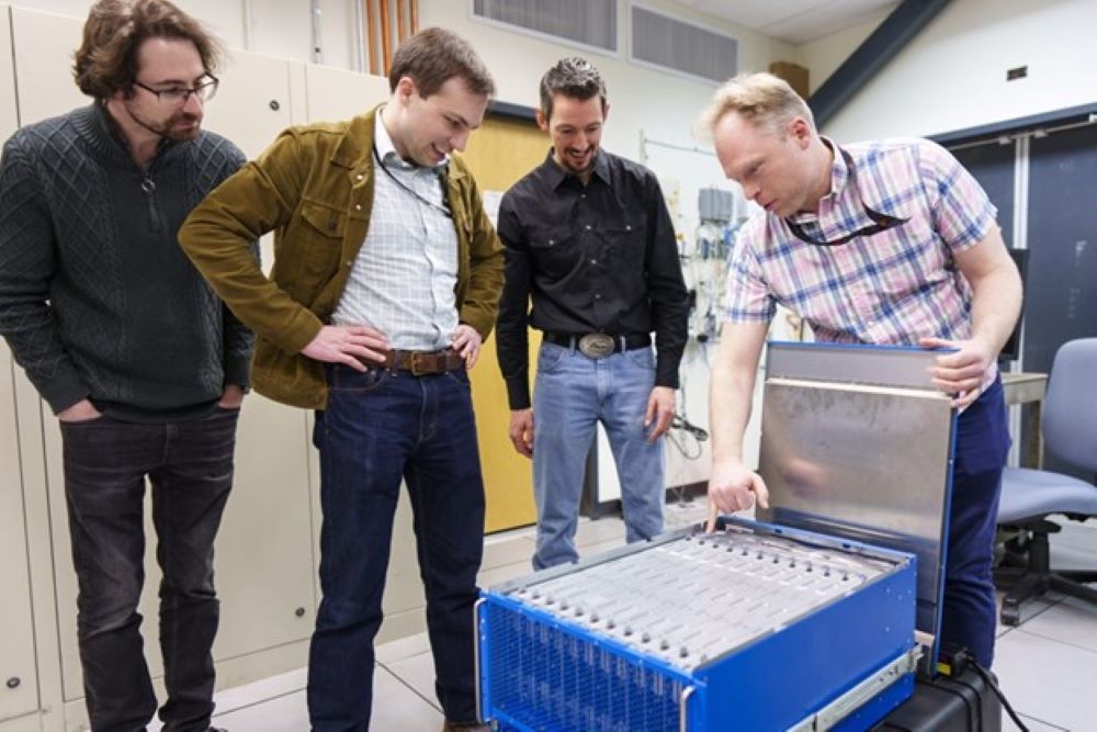 One man shows the Neuromorphic Computer to three other men