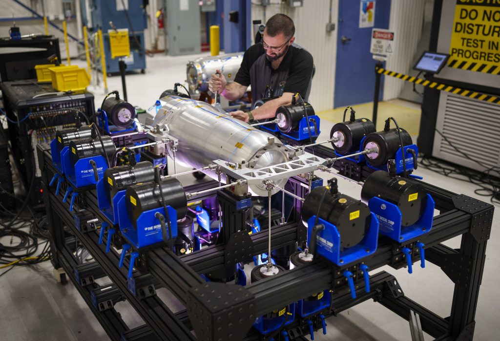 An engineer torques the clevis bolt that enables off center axis motion on the W80 MIMO shock and vibration test frame, holding an inert W80-4 unit.