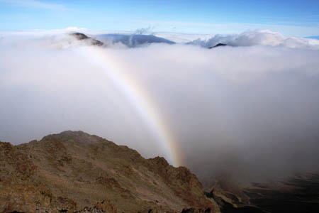 rainbow surrounded by clouds and mountains
