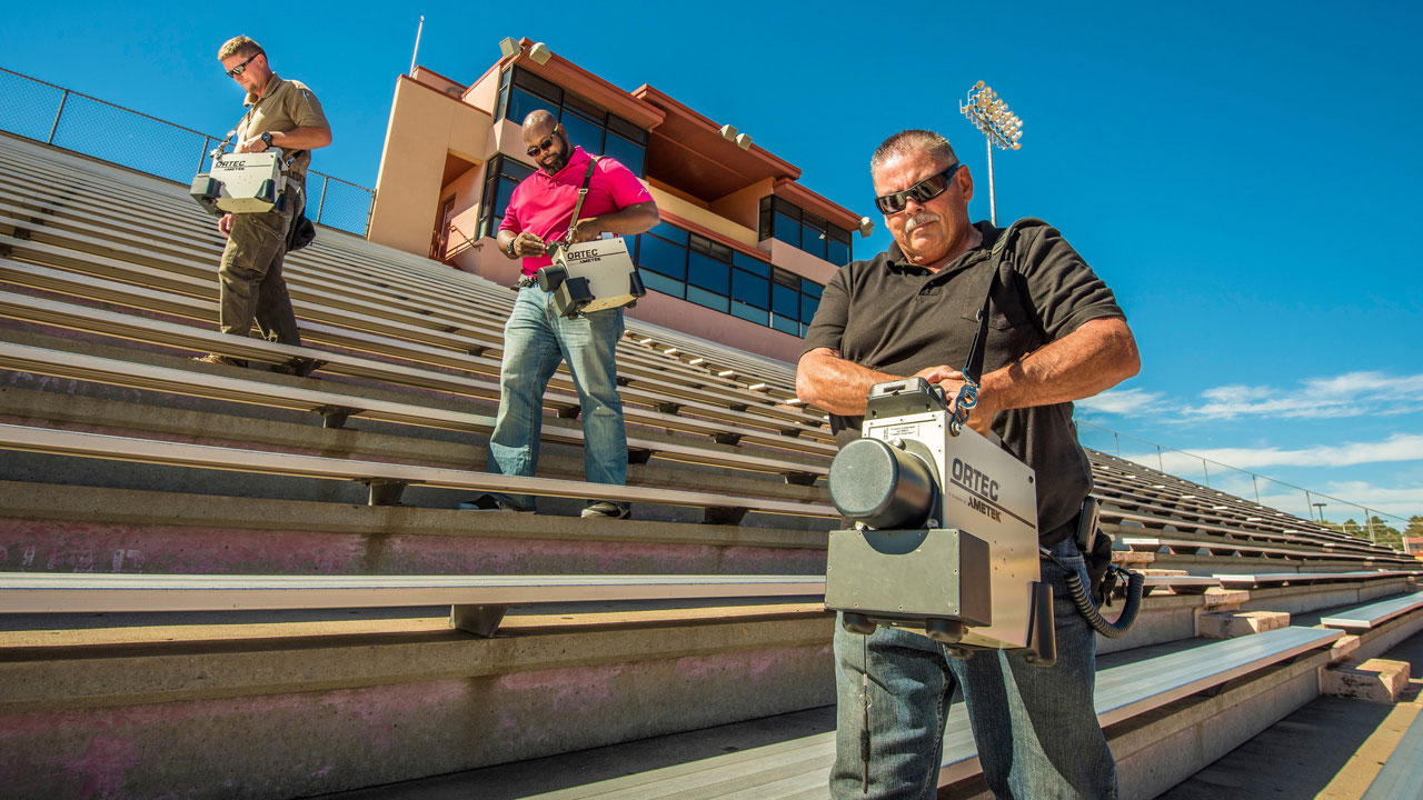 Men using SNIFFER to detect airborne chemicals in a sports stadium