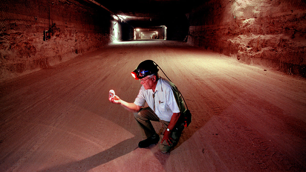 Man in a mine inspecting a piece of mineral