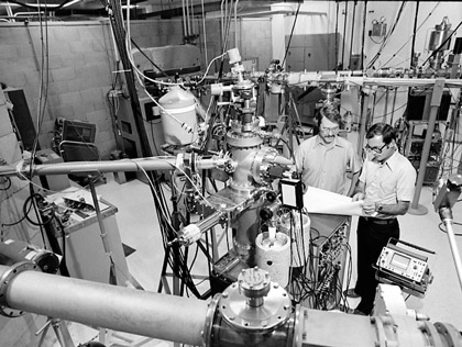 Barney Doyle and Paul Peercy discussing experimental set-up with Van de Graaff in old Ion Beam Laboratory, 1979