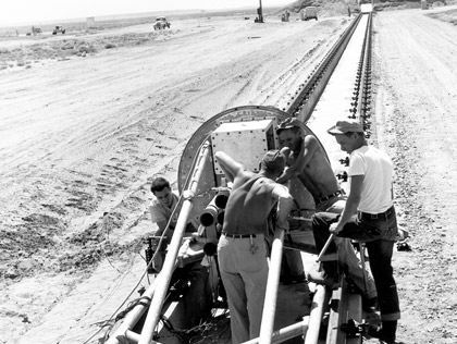 Walter Drake, Donald McCoy, Fred Brown and Sid Cook prepare for an early rocket-propelled sled impact test at Sandia’s new sled track in Tech Area III, 1954
