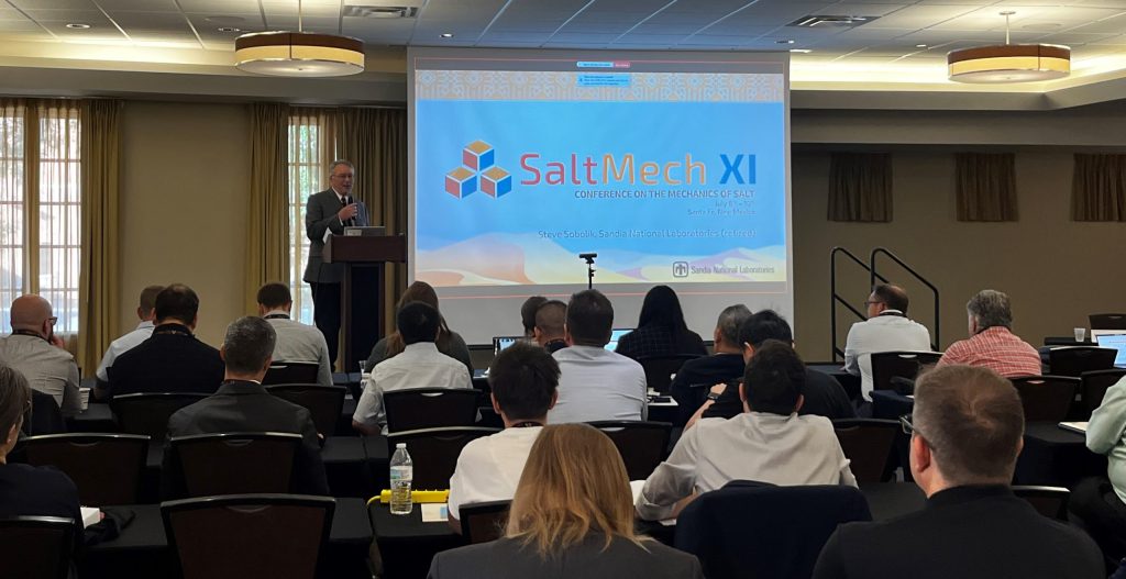 A man stands in front of a crowd in a conference room giving a presentation