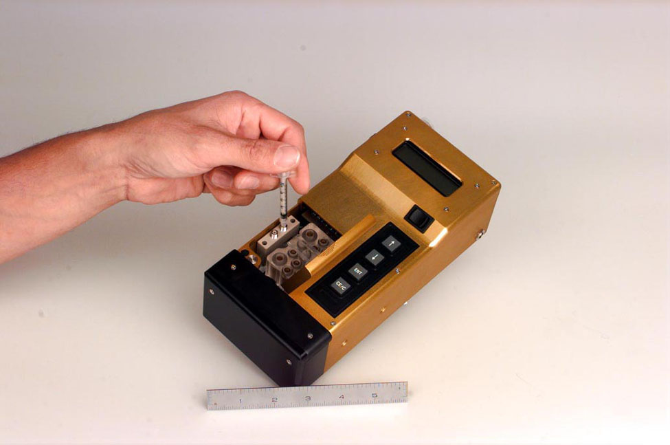 A user injects a sample into the liquid analysis system of the hand-held, integrated device for analyzing liquid and gas mixtures, under development at Sandia National Laboratories.