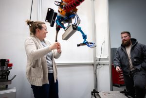 <strong>Hannah Sims, left, and Levi Van Bastian</strong> <strong>adjust a robotic arm on a Direct Energy Deposition system for additive manufacturing at Sandia National Laboratories' new CAMINO facility. </strong>(Photo by Craig Fritz) Click on the thumbnail for a high-resolution image.