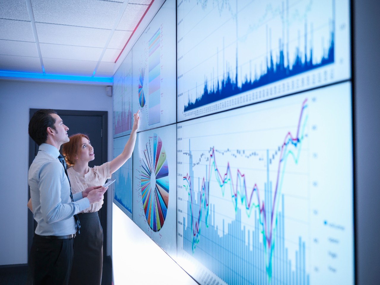 Employees looking at chart data on large screen