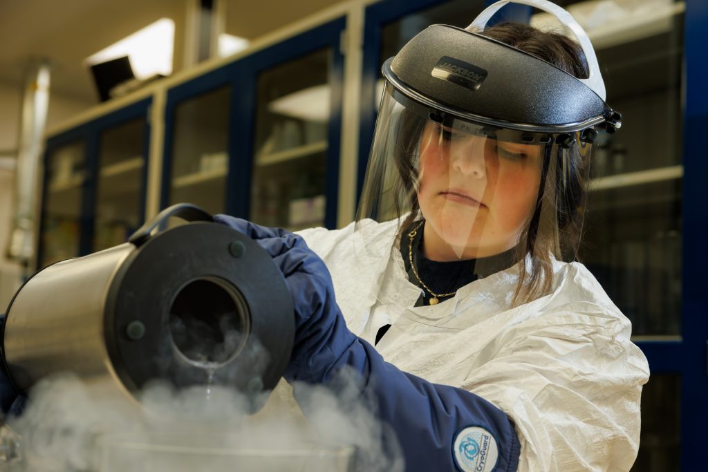 Woman working in lab with liquid nitrogen wearing protective head gear