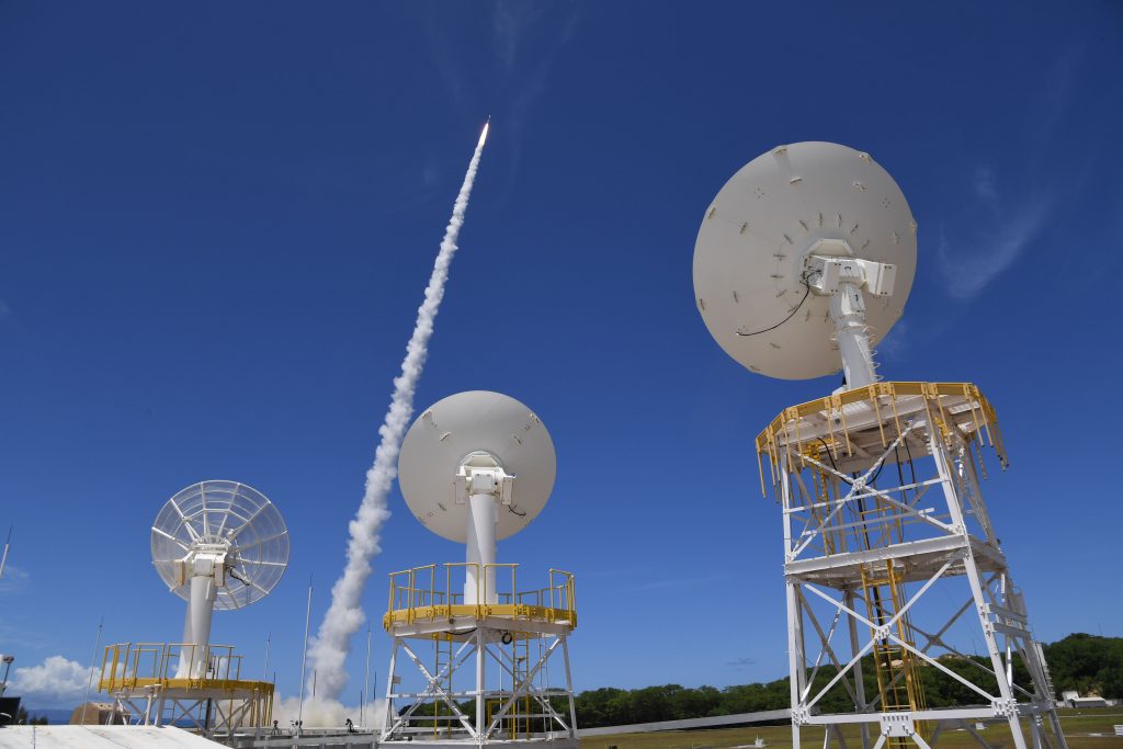 Missile shooting up toward sky behind satellites