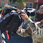 officer hands backpack to family at drive-up donation event