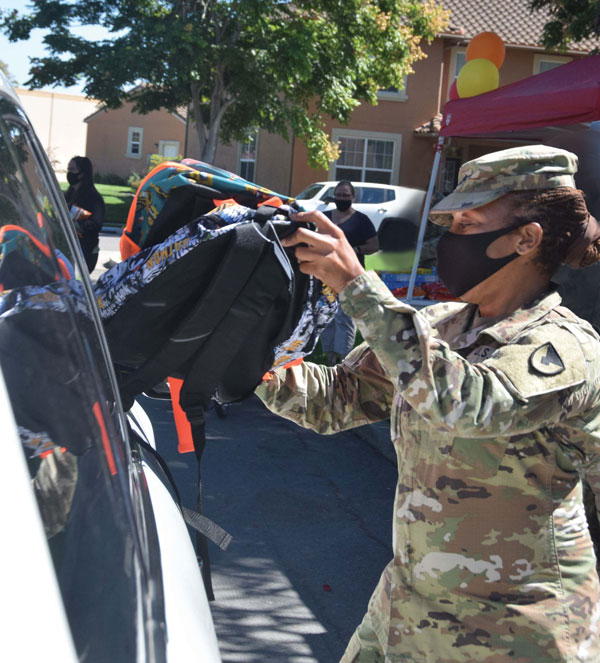 officer hands backpack to family at drive-up donation event