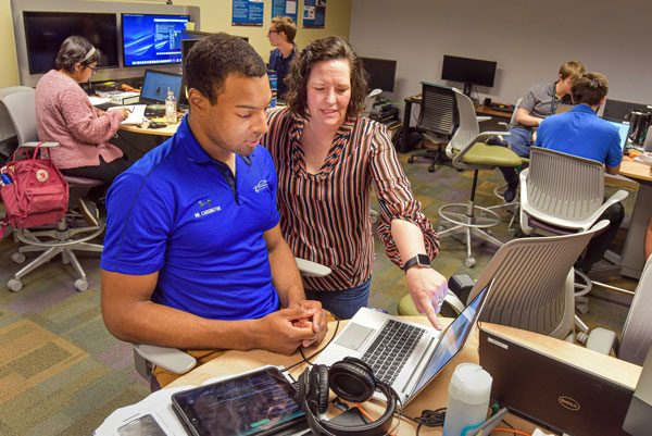 Tommie talks with intern in computer lab