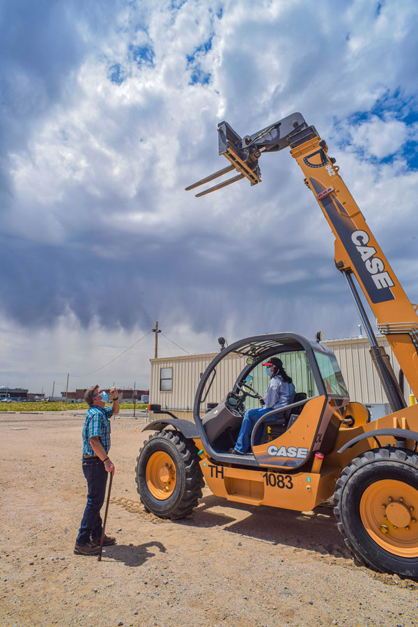 instructor stands by as student operates forklift