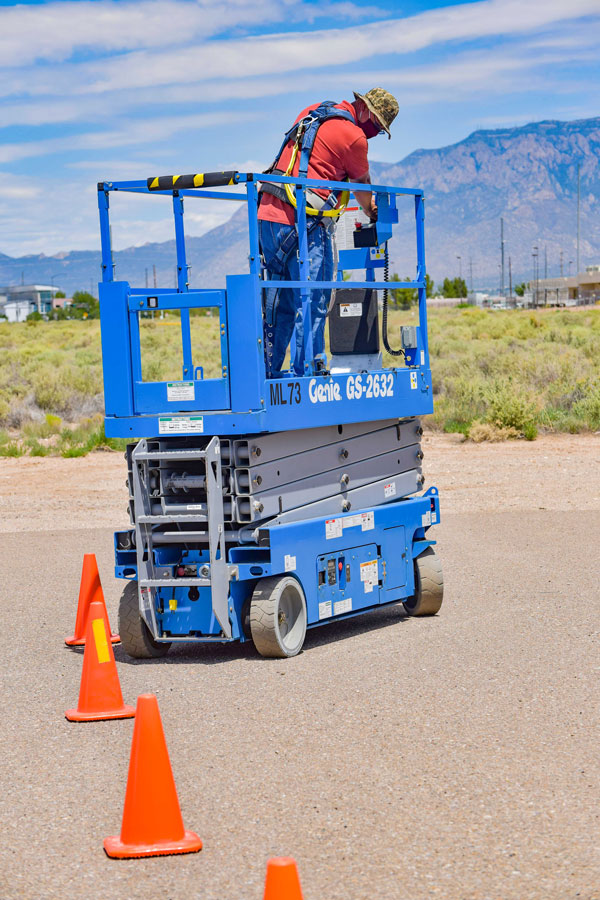 man drives scissor lift on slalom course