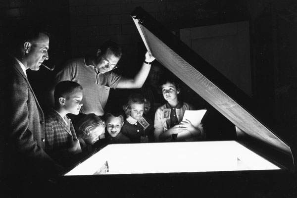 family day visitors in a dark room peer into a lit copy machine