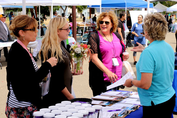 employees talk to health worker at booth