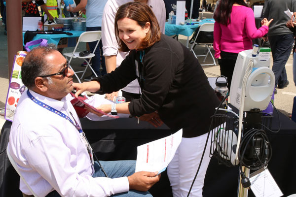 medical staff checks employee's blood pressure at booth