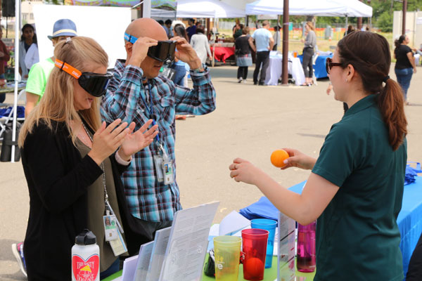 participants wear dark goggles and try to drop oranges in cups