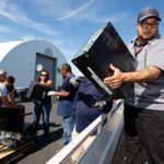 man loads computer onto flatbed trailer