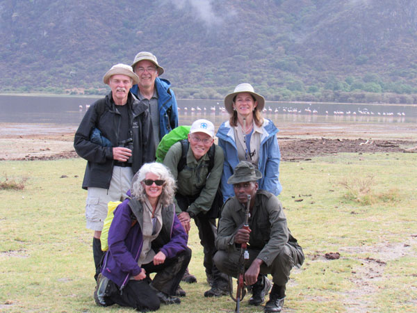 hiking group with guide on savanna with flamingos behind