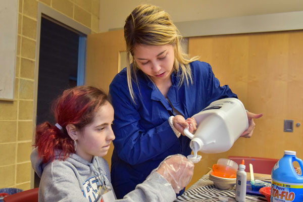 volunteer helps student with chemistry experiment