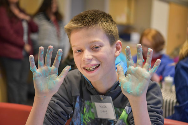 student shows hands covered in gooey blue substance