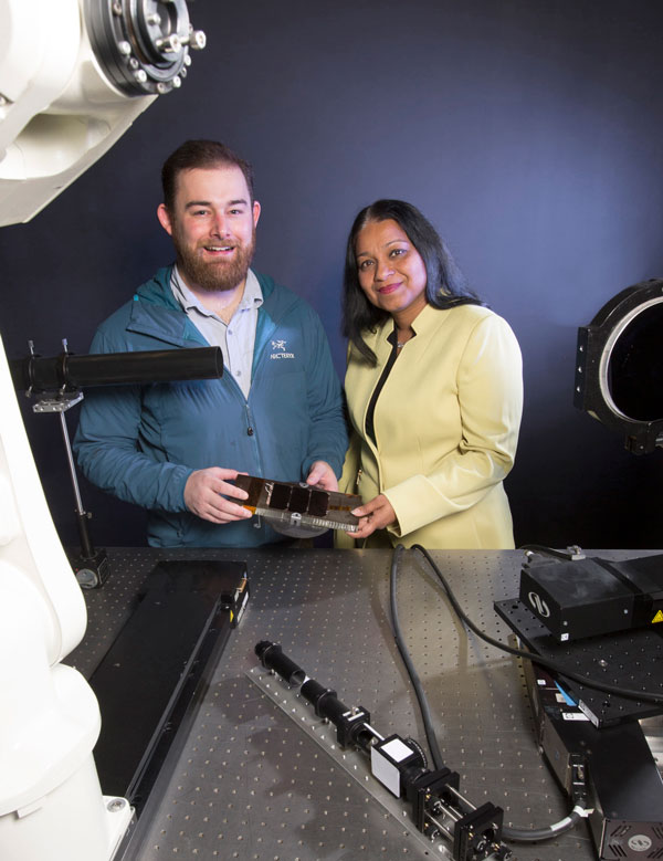 Sandia scientist and small business CEO hold titanium part in lab