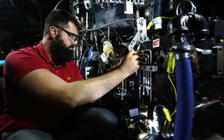 Researcher adjusts engine part in lab