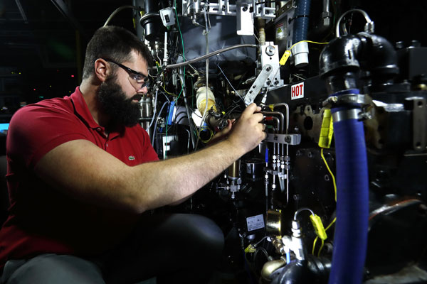 Researcher adjusts engine part in lab