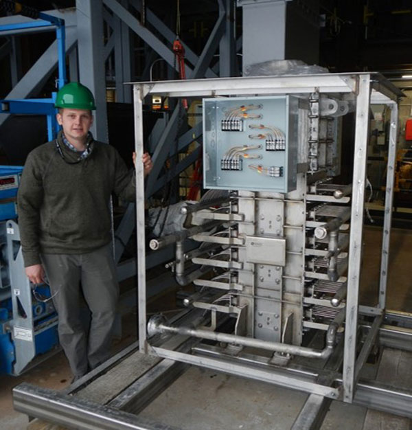 engineer stands next to particle-supercritical CO2 heat exchanger