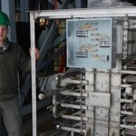 engineer stands next to particle-supercritical CO2 heat exchanger