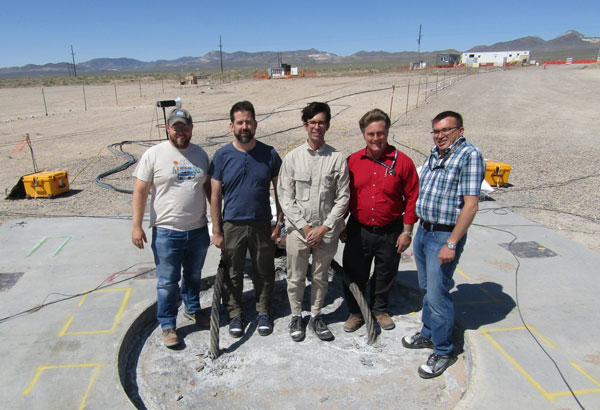 sandia researchers stand on filled borehole