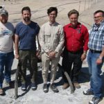 sandia researchers stand on filled borehole