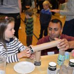Raheel Mahmood shows a student how to construct a roller coaster track for marbles