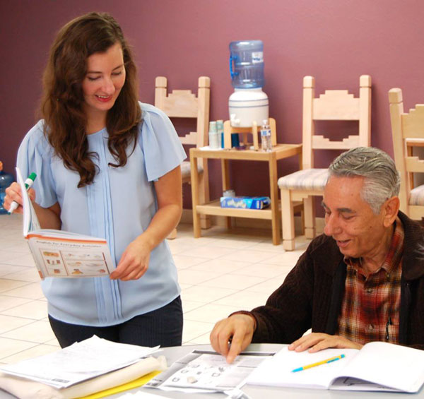 volunteer works with man on reading assignment