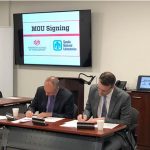 UNM's Craig White and Sandia's Scott Aeilts sign a memorandum of understanding